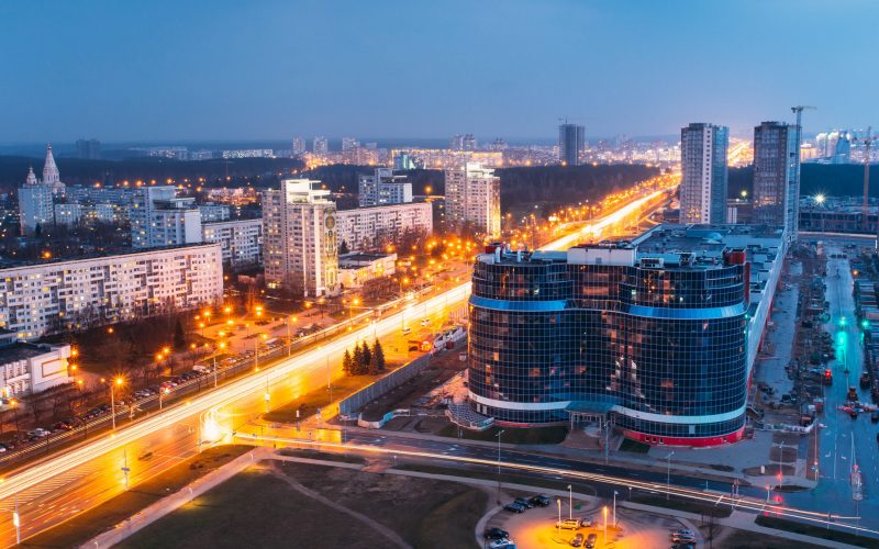Minsk, Belarus. Aerial View Cityscape In Bright Blue Hour Evening And Yellow Illumination Spring Twilight. Construction Of Building Dana Mall In Independence Avenue
